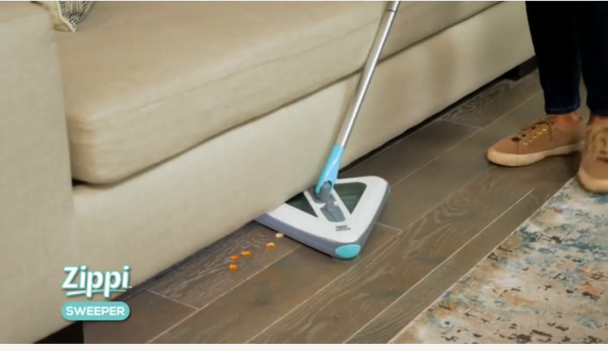 Zippi Sweeper cleaning under a sofa and along a rug